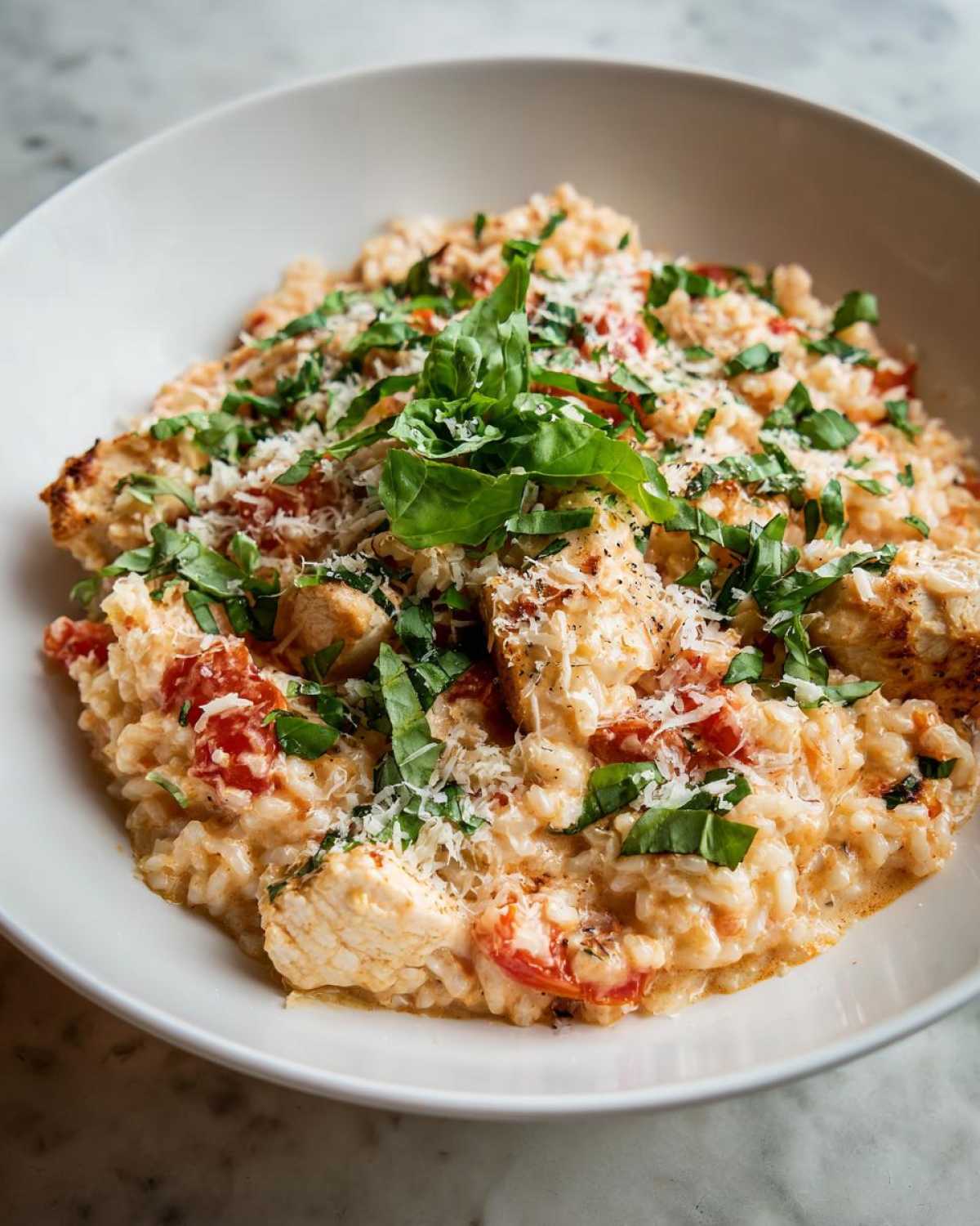 Close-up of One-Pot Creamy Tomato Basil Chicken and Rice topped with fresh basil and Parmesan.