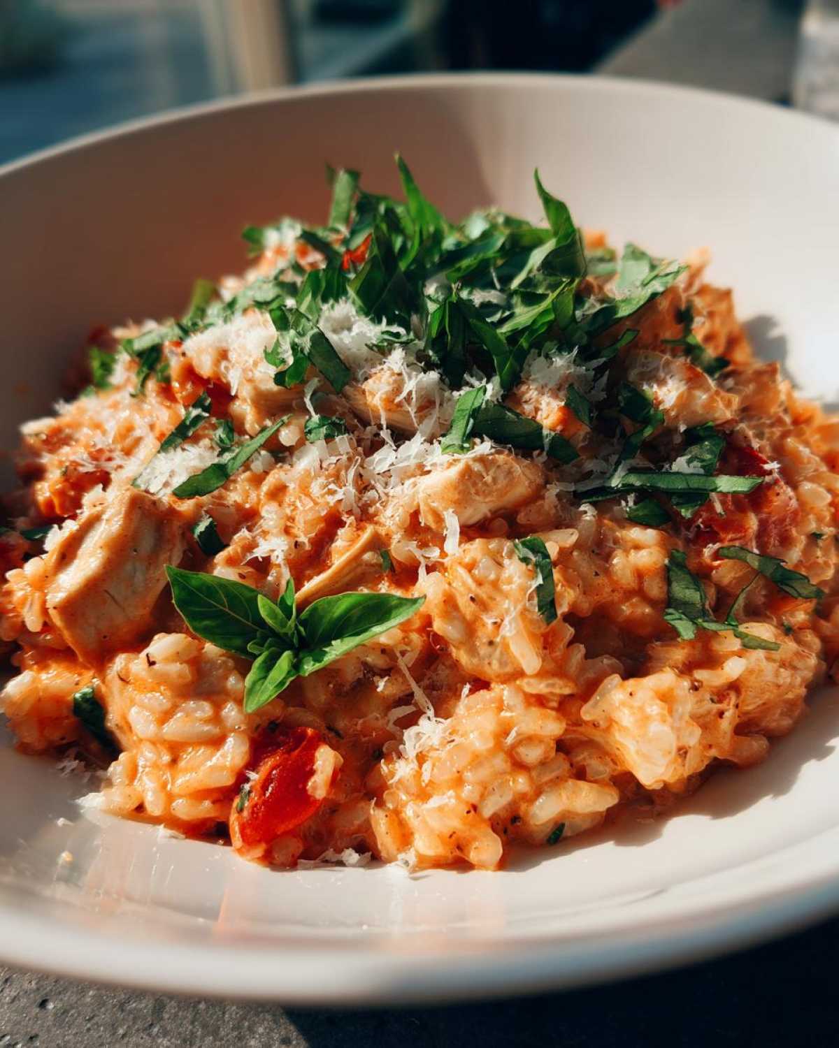 Close-up of One-Pot Creamy Tomato Basil Chicken and Rice topped with fresh basil and Parmesan.