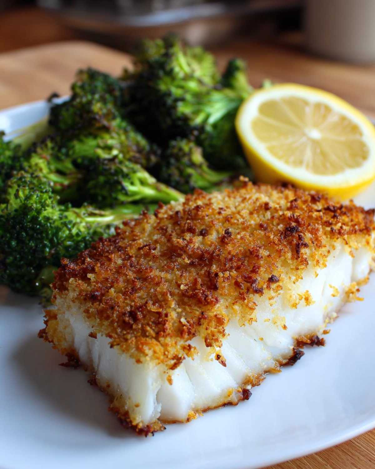 Close-up of Sheet Pan Parmesan Crusted Cod with roasted broccoli and a lemon slice.