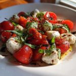 Close-up of a vibrant 15 Minute Caprese Salad featuring halved cherry tomatoes, mozzarella balls, and fresh basil drizzled with balsamic glaze.