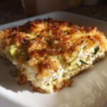 A square serving of Addictive Zucchini Casserole with a thick, golden-brown, crispy breadcrumb topping.