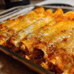 Close-up of freshly baked chicken enchiladas covered in melted cheddar and Monterey Jack cheese.