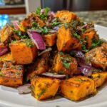 Close-up of roasted sweet potato chunks mixed with red onion and herbs in a vibrant sweet potato salad.