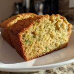 Two slices of moist, golden brown zucchini bread recipe showing flecks of green shredded zucchini inside.