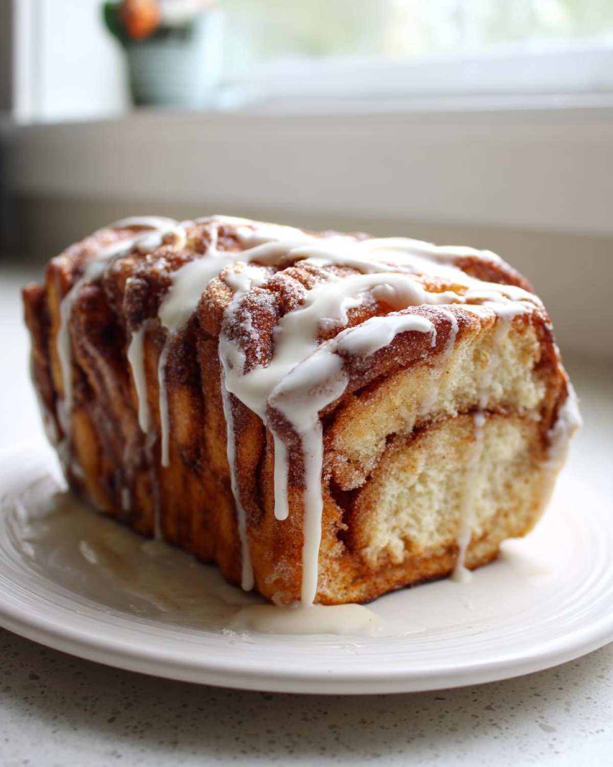 A loaf of freshly baked Amish Cinnamon Bread drizzled generously with white vanilla icing.