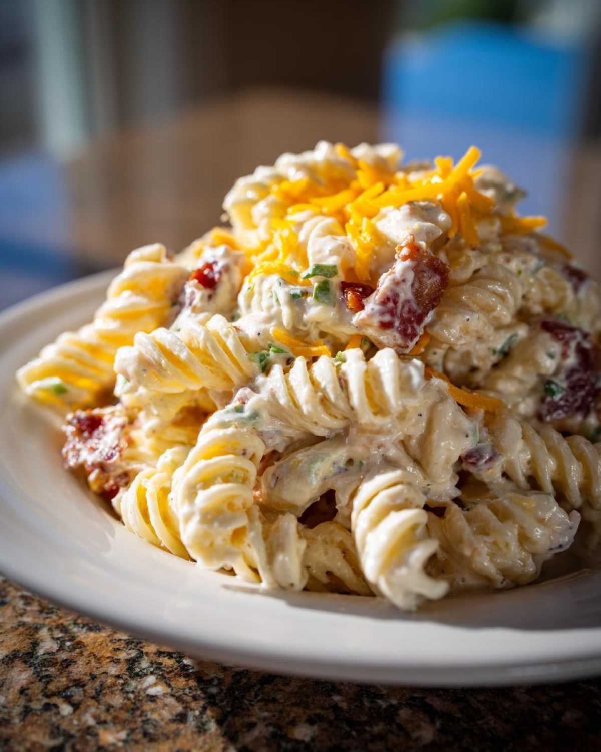 Close-up of a serving of Bacon Ranch Pasta Salad featuring rotini pasta coated in creamy dressing, bacon bits, and topped with shredded cheddar cheese.