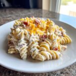 A serving of creamy Bacon Ranch Pasta Salad made with rotini pasta, bacon bits, and topped with shredded cheddar cheese.