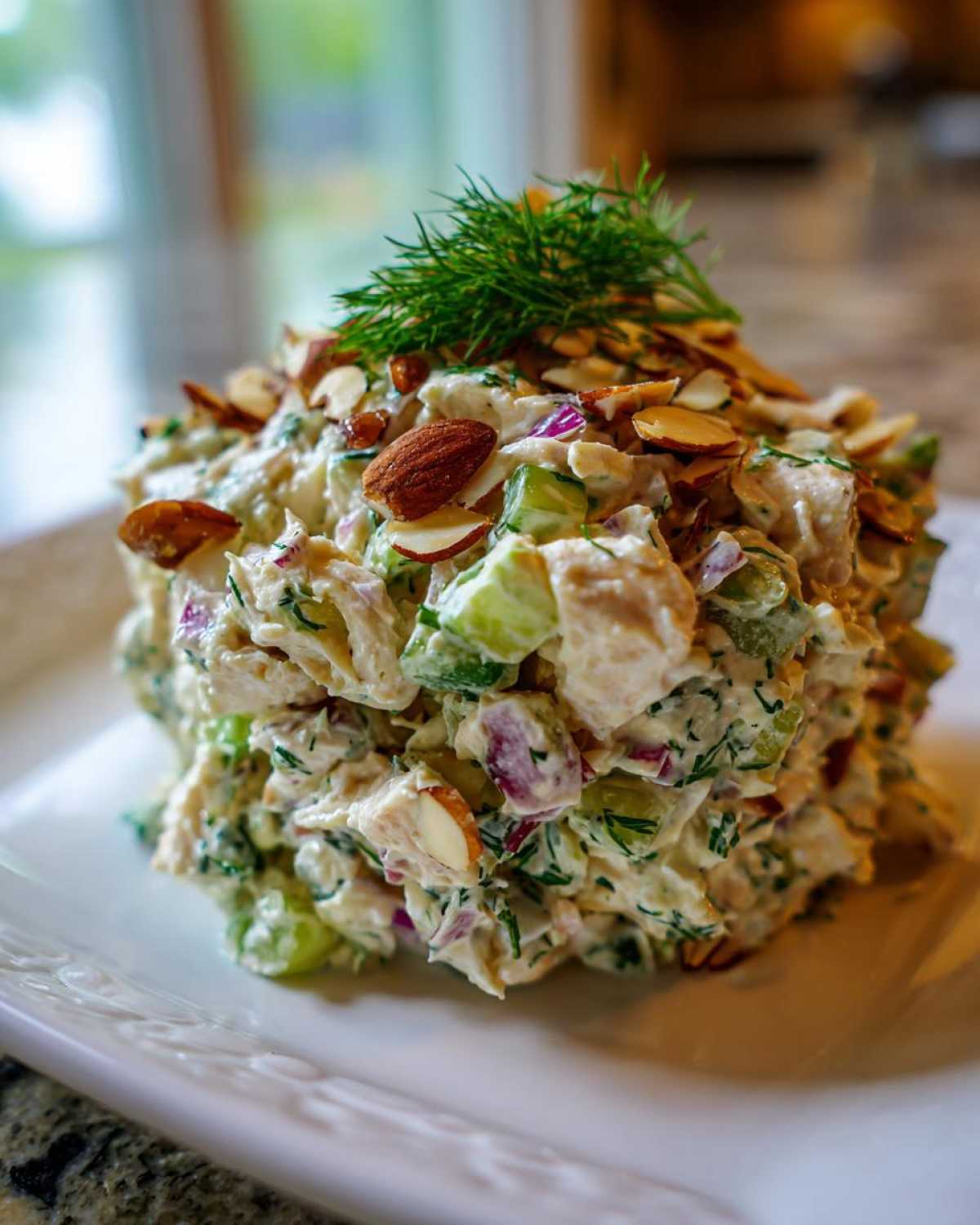 A scoop of creamy Baked Marinated Chicken Salad topped with sliced almonds and fresh dill.