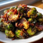 Close-up of perfectly roasted Balsamic Glazed Brussels Sprouts with Bacon pieces on a white plate.