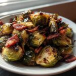 A close-up of roasted Balsamic Glazed Brussels Sprouts with Bacon served in a white bowl.