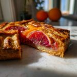 A slice cut from a golden, flaky Blood Orange and Rhubarb Geometric Galette, showing vibrant red fruit inside.