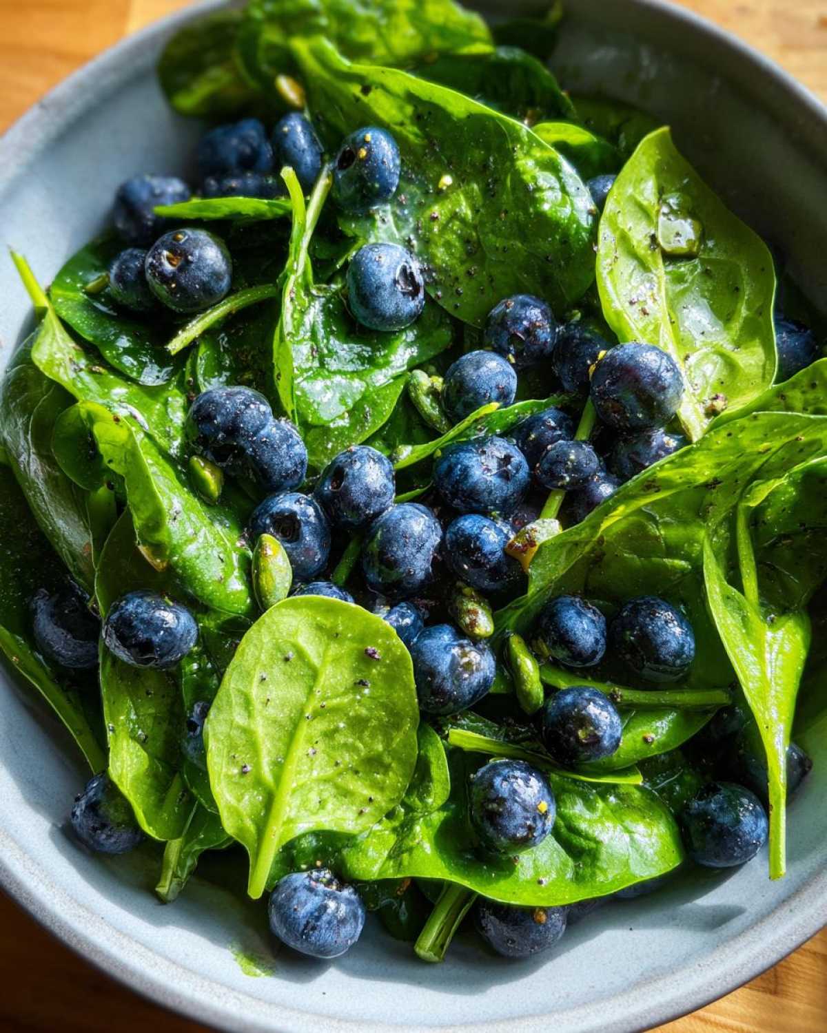 Close-up of a fresh Blueberry Pistachio Spring Salad featuring spinach leaves, blueberries, and pistachios.