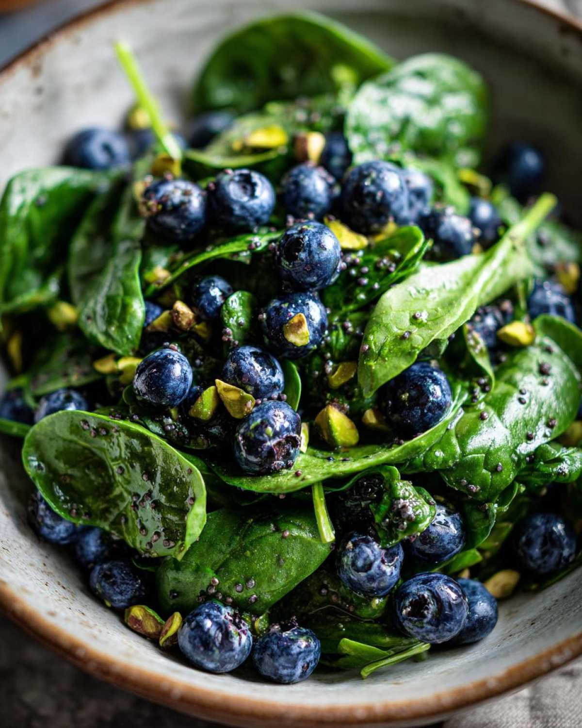 Close-up of a vibrant Blueberry Pistachio Spring Salad featuring fresh spinach, blueberries, and chopped pistachios.