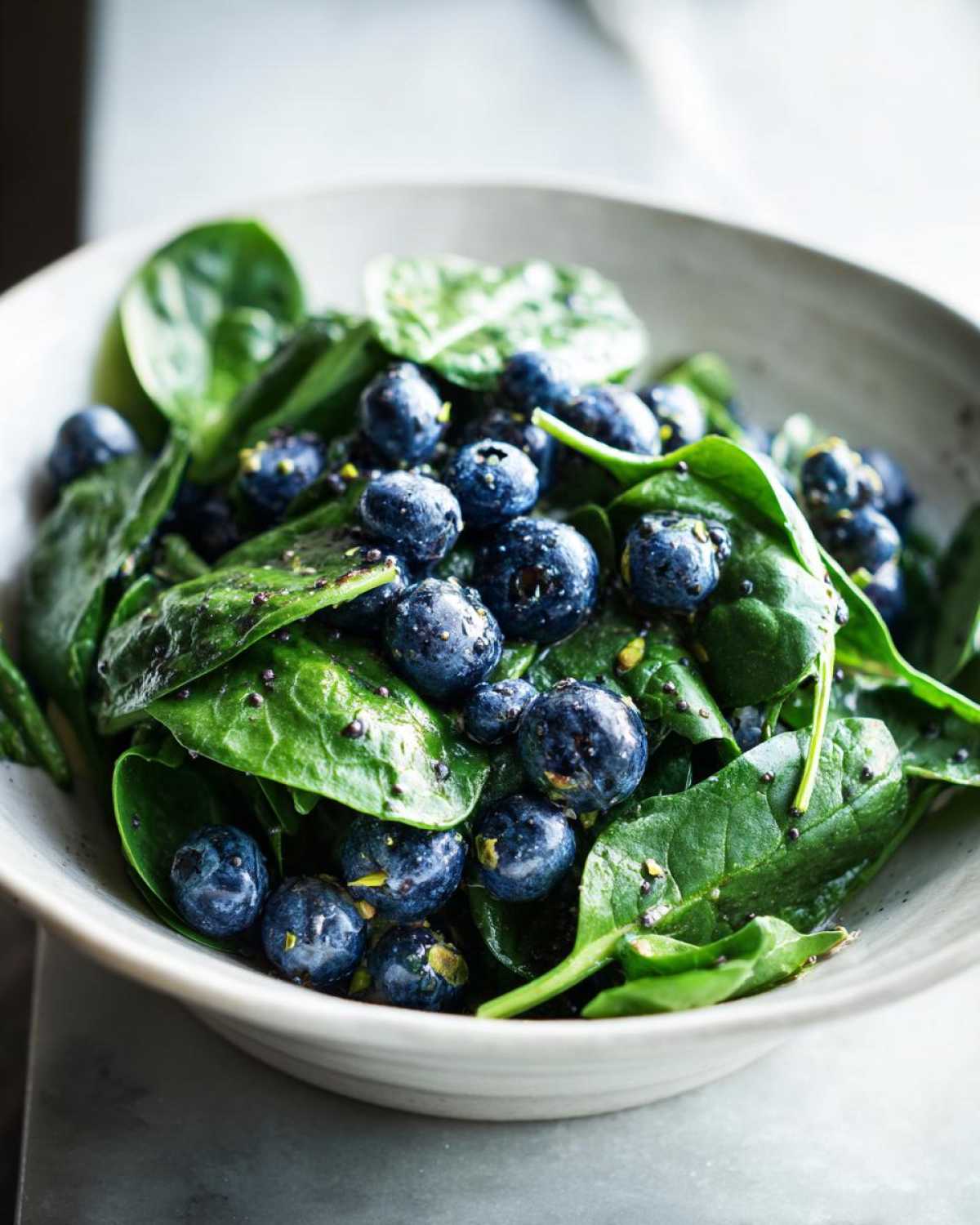 Close-up of a vibrant Blueberry Pistachio Spring Salad featuring fresh spinach leaves and plump blueberries.