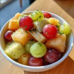 Close-up of a vibrant bowl of Boat Snacks: Fresh Fruit Salad featuring grapes, melon chunks, and poppy seeds.