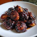 Close-up of roasted Brussels sprouts heavily coated in a thick, dark Sticky Brussels Sprouts Glaze.