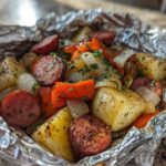 Close-up of seasoned Campfire Potatoes mixed with sausage, onions, and carrots cooked in a foil packet.
