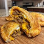 Close-up of cheesy pocket tacos cut open, showing ground meat filling and melted cheddar cheese.