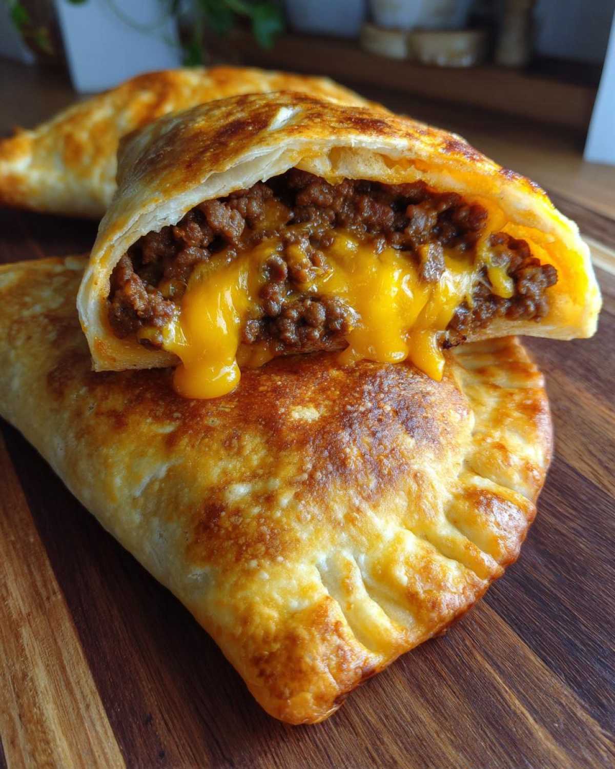 Close-up of a cheesy pocket taco cut in half, showing seasoned ground beef and melted cheddar cheese oozing out.