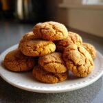 A tempting stack of chewy pumpkin snickerdoodles, generously coated in granulated sugar, sitting on a white plate.