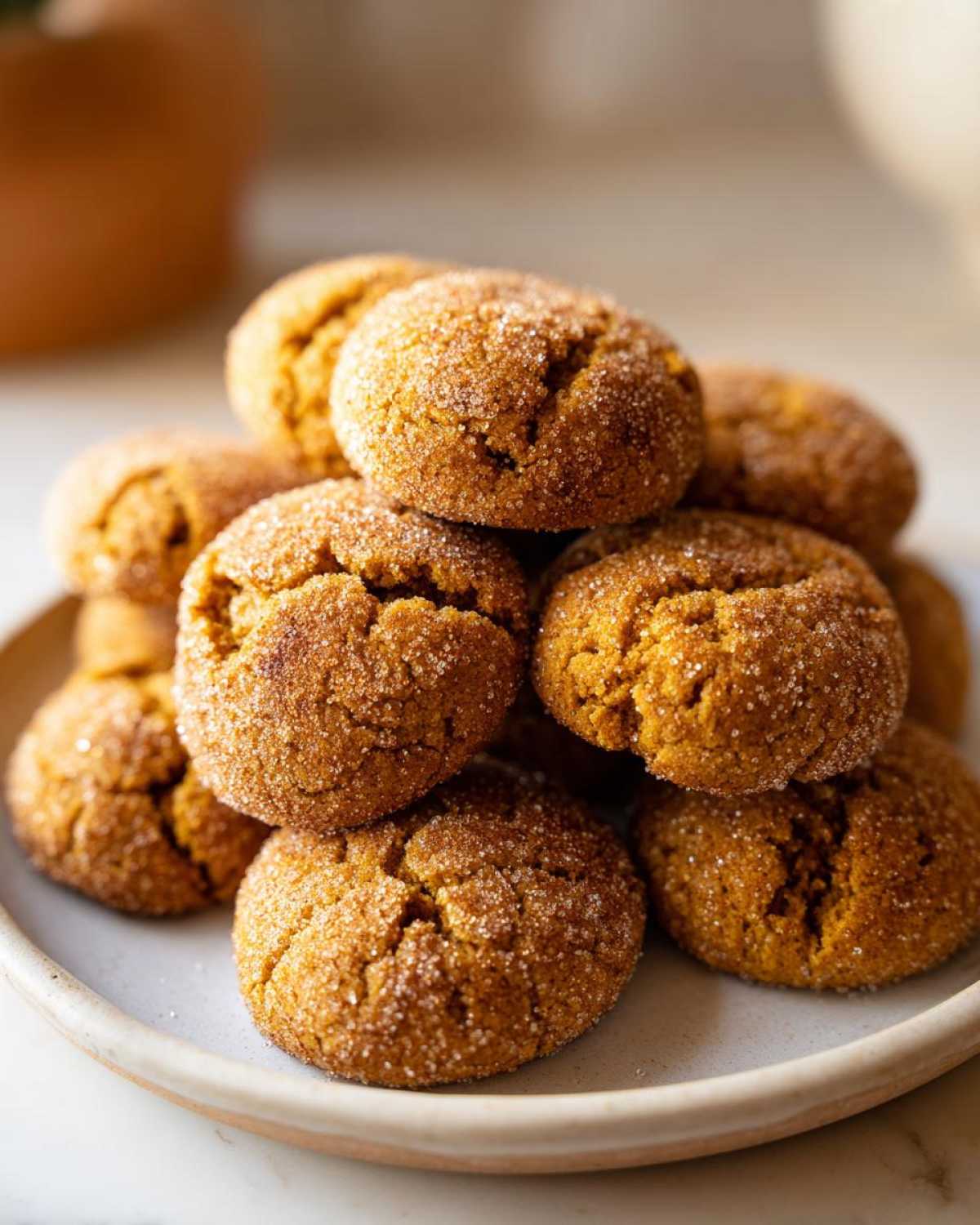 A close-up stack of chewy pumpkin snickerdoodles generously coated in sparkling cinnamon sugar.