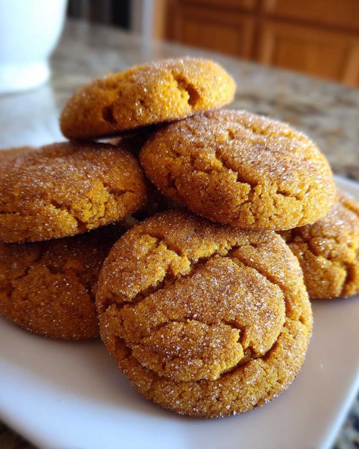 A close-up stack of chewy pumpkin snickerdoodles generously coated in cinnamon sugar.