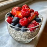 Close-up of creamy Chia Seed Pudding with Fresh Berries, including raspberries, blueberries, and sliced strawberries.