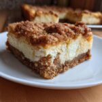 A close-up of a single serving of churro cheesecake bars showing the thick graham cracker crust, creamy filling, and cinnamon sugar topping.