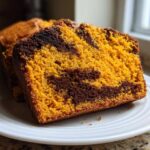 Close-up of two slices of Cinnamon Swirl Pumpkin Bread showing vibrant orange pumpkin batter marbled with dark chocolate swirl.