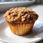 A close-up of a freshly baked Coffee Cake Muffins featuring a thick, sugary cinnamon crumb topping.