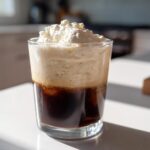 A glass of iced coffee topped with thick, frothy Copycat Starbucks Vanilla Sweet Cream Cold Foam.