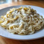 A close-up of creamy fettuccine tossed in rich cottage cheese alfredo sauce and topped with cracked black pepper.