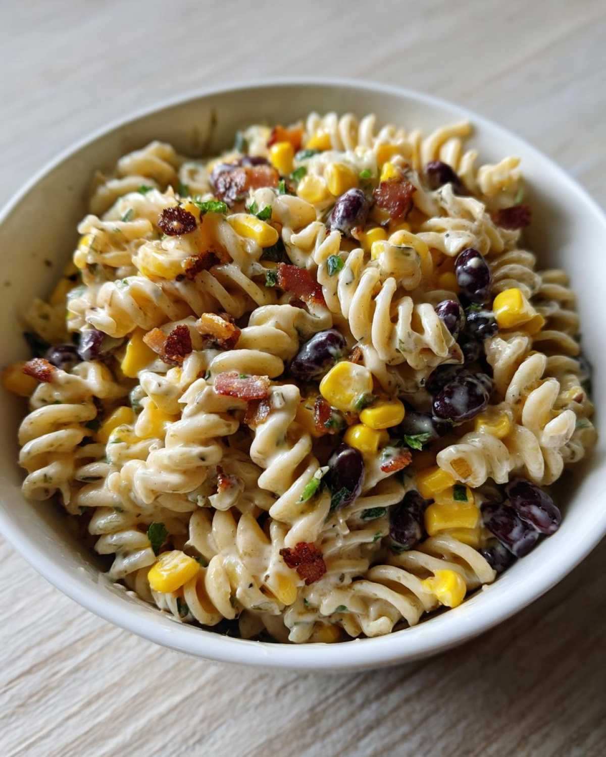Close-up of Cowboy Pasta Salad featuring rotini pasta, black beans, corn, and bacon bits in a creamy dressing.