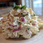 A generous mound of creamy crab salad featuring shredded crab, red onion pieces, and topped with fresh parsley.