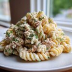 Close-up of a mound of Creamy Tuna Pasta Salad made with rotini pasta, tuna, and fresh dill on a white plate.