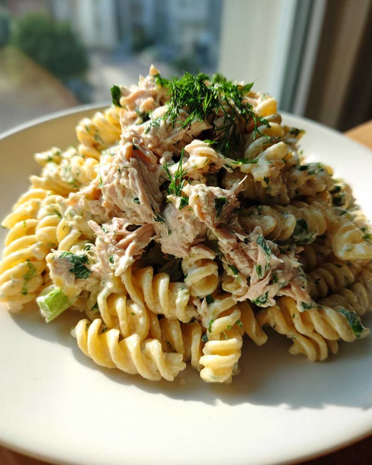 Close-up of a serving of Creamy Tuna Pasta Salad made with fusilli pasta, topped with flaked tuna and fresh dill.