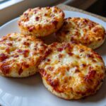 Four perfectly baked english muffin pizza halves topped with melted, bubbly, and slightly browned cheese.