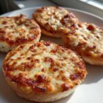 Four perfectly baked english muffin pizza halves topped with melted, browned mozzarella cheese.