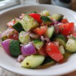 Close-up of a vibrant Cucumber Onion Tomato Salad with chunks of cucumber, red tomato, and purple onion dressed lightly.