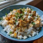 A close-up of the Easy Street Corn Chicken Rice Bowl featuring seasoned chicken pieces over white rice, topped with cotija cheese and cilantro.
