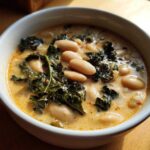 Close-up of a bowl of Easy Tuscan White Bean Soup featuring white beans and dark green kale in a creamy broth.
