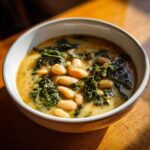 Close-up of a creamy bowl of Easy Tuscan White Bean Soup featuring cannellini beans and wilted kale.