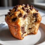 Close-up of a fluffy chocolate chip muffin recipe, showing the moist interior and generous chocolate chips.