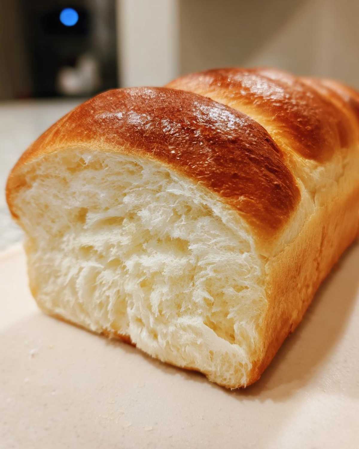 Close-up of a freshly baked milk bread loaf showing its incredibly soft, white, and fluffy interior crumb.