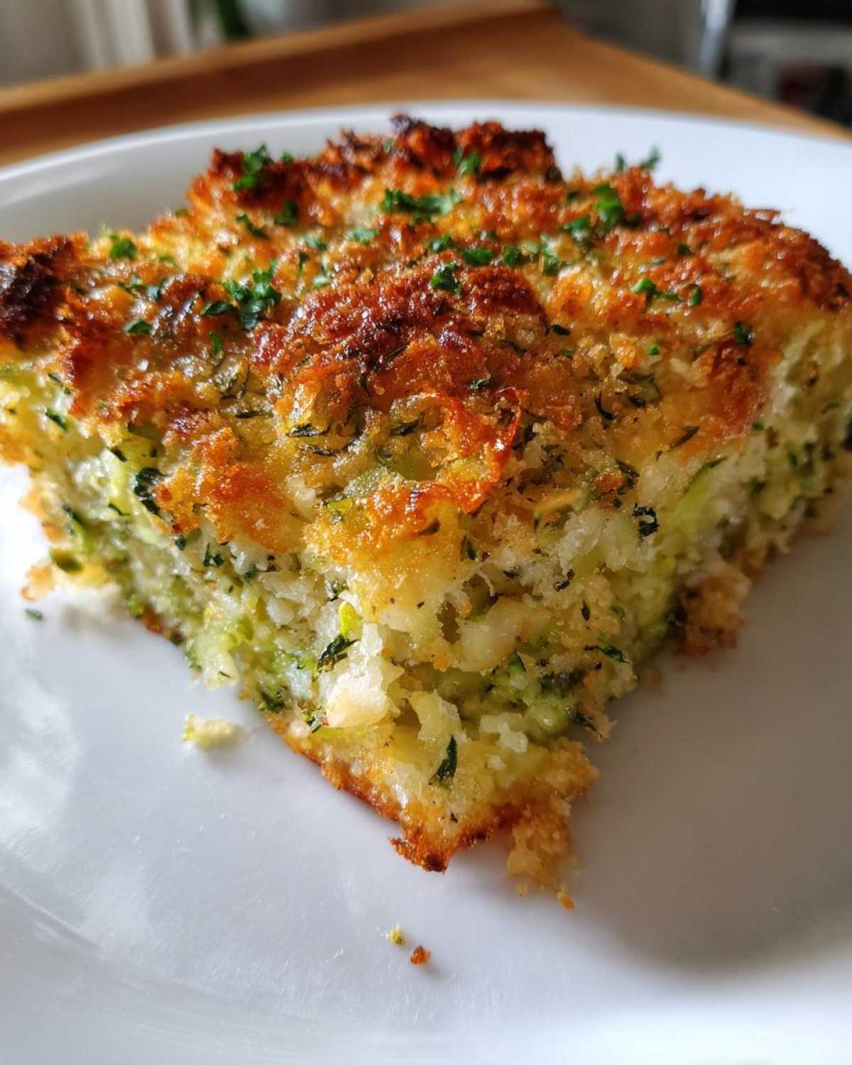 Close-up of a square slice of Garlic Parmesan Zucchini Casserole with a golden, crispy topping.