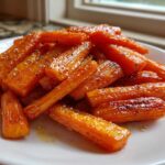 A close-up of perfectly glazed roasted carrots sprinkled with flaky salt, ready to serve.