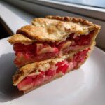 Two stacked slices of Grandma's Rhubarb Pie with Lard Crust showing flaky golden pastry and bright red rhubarb filling.