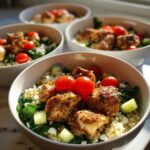 Close-up of a Greek Yogurt Marinated Chicken Bowls featuring seasoned chicken, quinoa, spinach, cucumber, and cherry tomatoes.