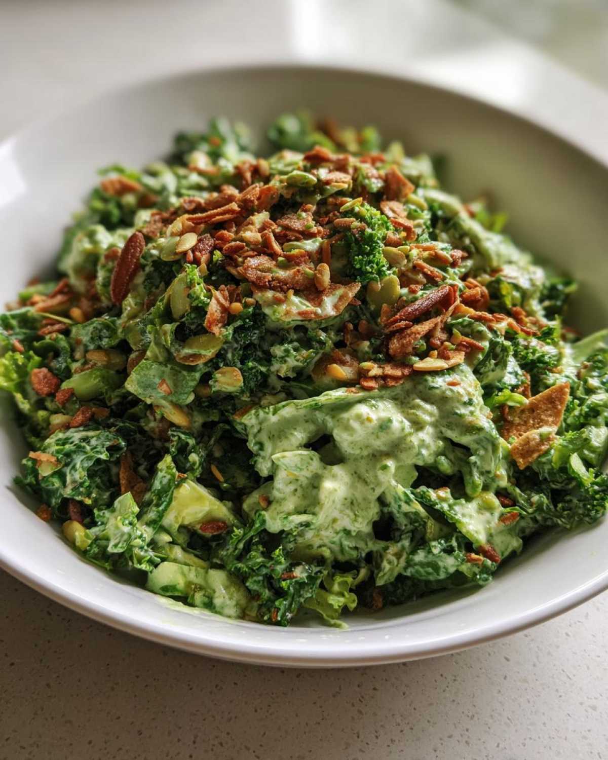 A close-up of the Green Goddess Crunch Salad tossed in creamy green dressing and topped with crunchy nuts and seeds.
