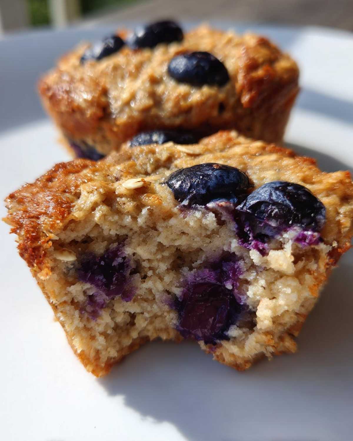 A close-up view of a bitten cottage cheese muffin showing the moist interior packed with blueberries.